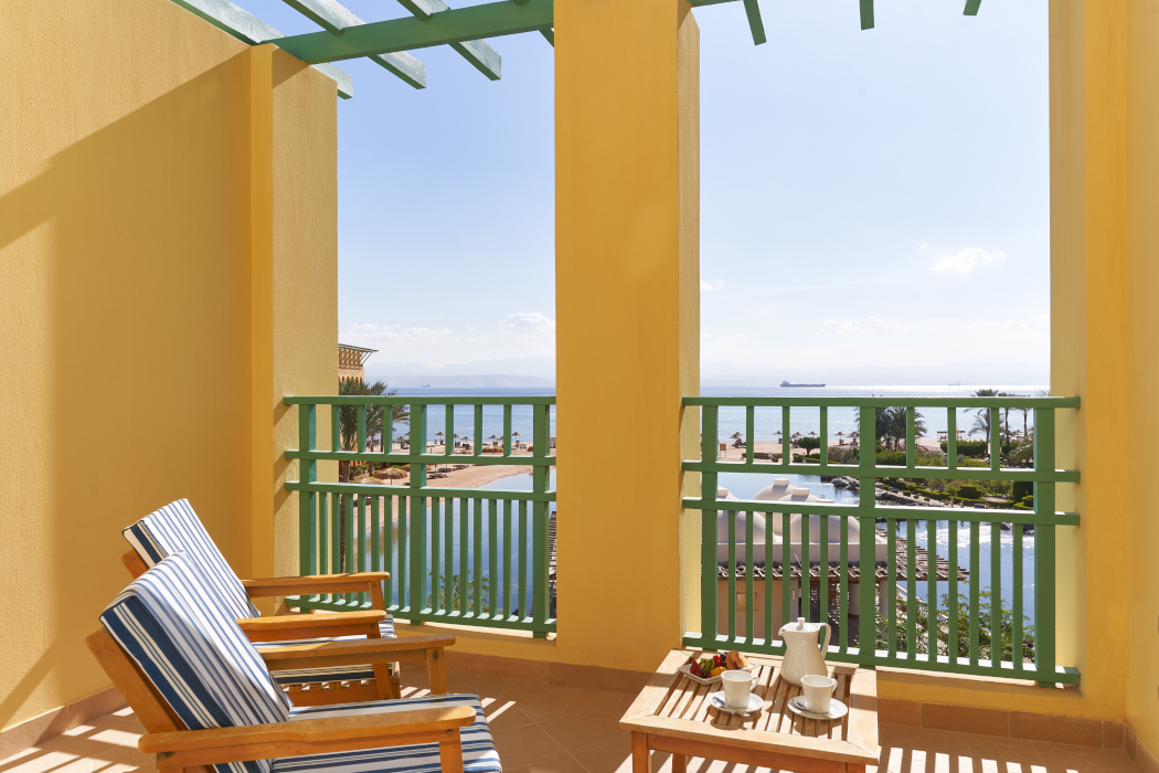 Lagoon view room terrace with 2 chairs and table at Strand Beach Resort, Taba Heights.