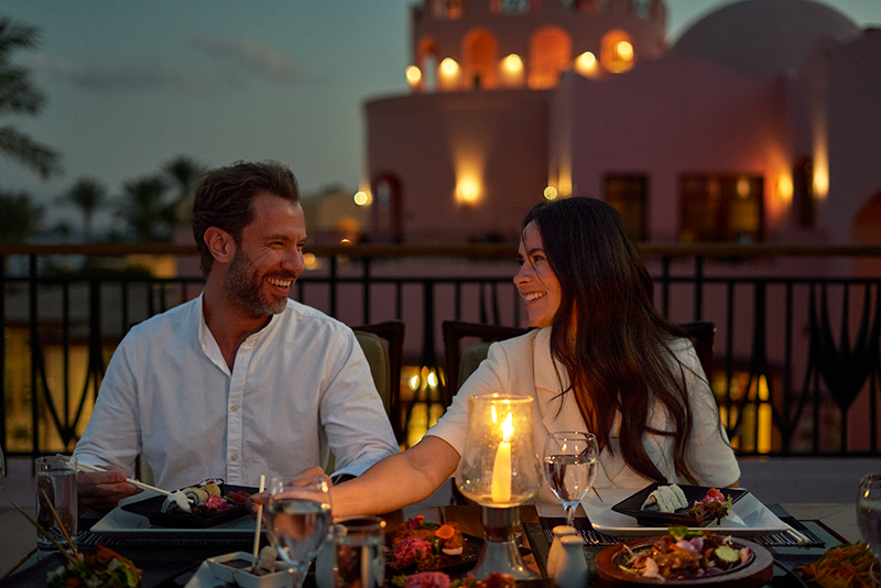 couple happily enjoying a romantic candlelit dinner at taba heights hotels