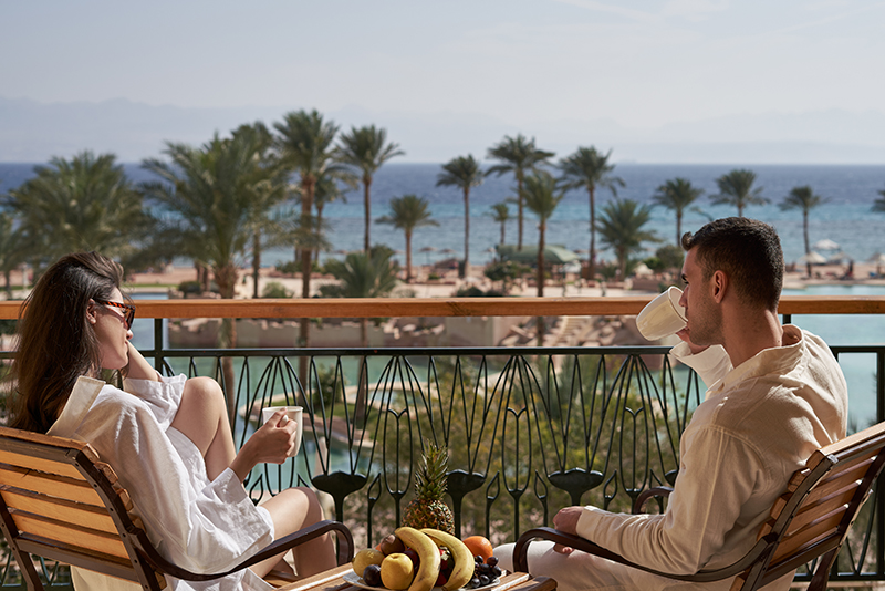 couple enjoying morning coffee at their hotel room with a sea view at taba heights hotels